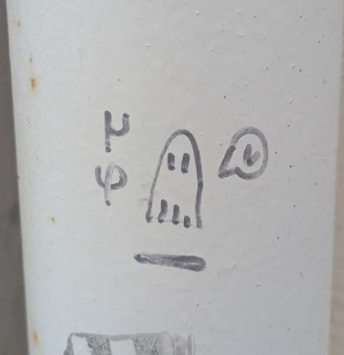 Small ghost doodle with black pen on grey pipe.