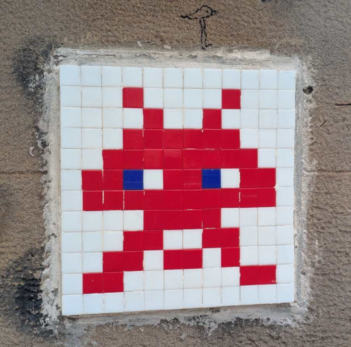 red space invader look alike. done with small red tiles with white tiles as background on a grey wall